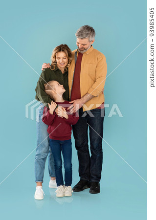Middle Aged Parents Embracing Daughter Smiling Standing Together In Studio 93985405