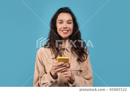 Portrait of happy millennial caucasian brunette woman in casual typing on smartphone 93985522
