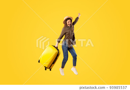 Joyful Traveler Lady With Suitcase Jumping Over Yellow Background Joyful Traveler Lady With Suitcase Jumping Over Yellow Background 93985537