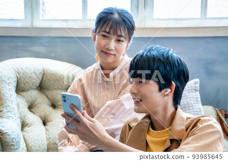 Young couple listening to music on smartphone Young couple listening to music on smartphone 93985645