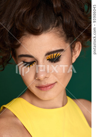 young curly woman with creative make-up in yellow dress 93986045
