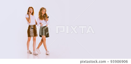 Portrait of beautiful young women with bright makeup walking, talking on phone isolated on grey background 93986906