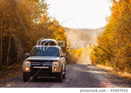 Mitsubishi Pajero on scenic autumn road in the forest 93987650