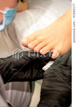 The podiatry doctor examines the toenails on the female foot The podiatry doctor examines the toenails on the female foot 93988177