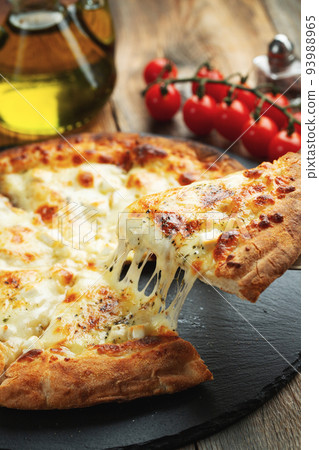 A slice of hot Italian pizza with stretching cheese. Pizza four cheeses with basil. 93988965