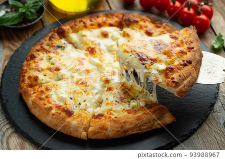 A slice of hot Italian pizza with stretching cheese. Pizza four cheeses with basil. 93988967