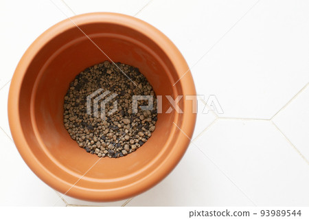 Flowerpot with expanded clay for planting plants on a white tile top view. Flowerpot with expanded clay for planting plants on a white tile top view. 93989544
