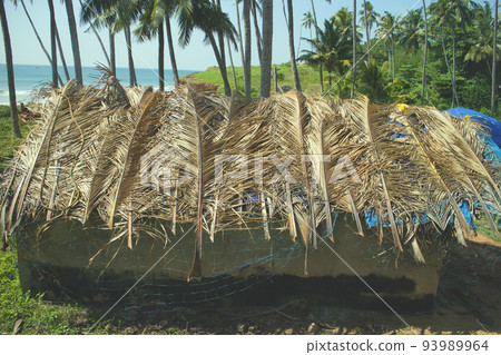 Indian hut on seafront, covered with plastic, palm leaves and fishing net. 93989964