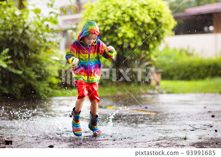 Kids in puddle in autumn rain. Waterproof wear Kids in puddle in autumn rain. Waterproof wear 93991685