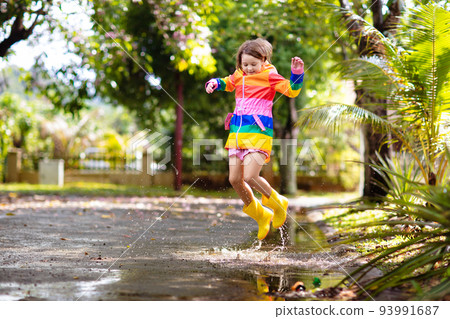 Kids in puddle in autumn rain. Waterproof wear Kids in puddle in autumn rain. Waterproof wear 93991687