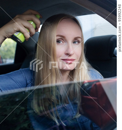 Dry shampoo. Blonde girl sprays shampoo on her hair. The problem of oily hair while traveling. An emergency remedy for excessive sebum production. Make your head clean without water 93992248