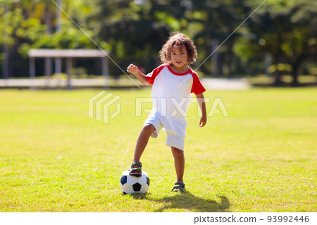 Cute curly little boy playing football. Kids play. 93992446
