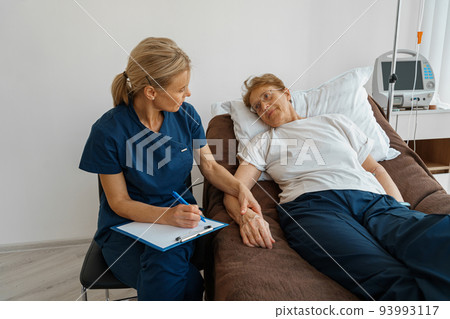 Doctor measures patient's heart rate and makes note during treatment in a hospital ward Doctor measures patient's heart rate and makes note during treatment in a hospital ward 93993117