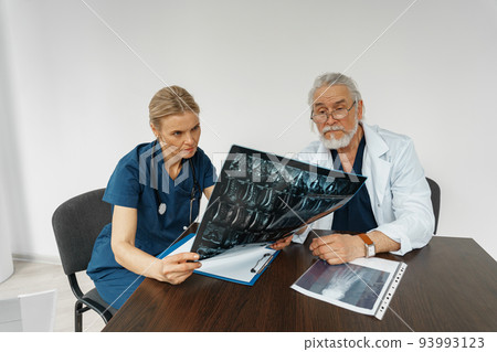 Team of doctors discuss results of X-Ray or MRI scan of patient's spine in medicine office of clinic 93993123
