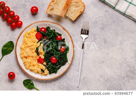 Cooked omelette and spinach with tomatoes on a light background 93994677