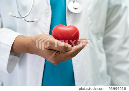 Doctor holding a red heart in hospital ward, healthy strong medical concept. Doctor holding a red heart in hospital ward, healthy strong medical concept. 93994916