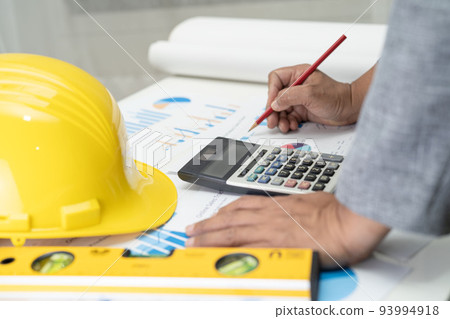 Asian engineer with architectural house plan project blueprint, graph and yellow helmet and engineering construction tools. Asian engineer with architectural house plan project blueprint, graph and yellow helmet and engineering construction tools. 93994918