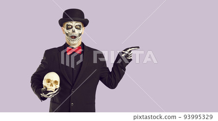 Man in Halloween costume with surprised and shocked expression is pointing at advertising space. 93995329