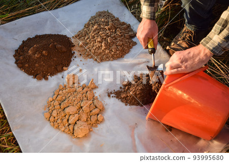 Man farmer arranging soil samples, arranging types of soil outdoors Man farmer arranging soil samples, arranging types of soil outdoors 93995680