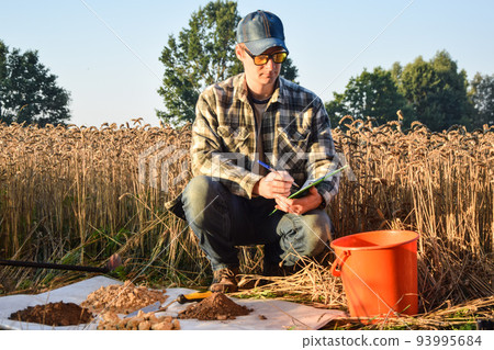 Agriculturist taking notes in soil sampling information sheet at field 93995684