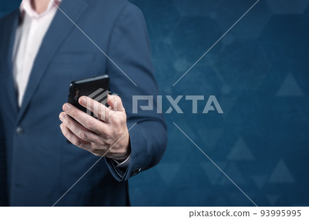 Online business. businessman holding the cell mobile phone on dark blue background. copy space. internet, cellular technology concept Online business. businessman holding the cell mobile phone on dark blue background. copy space. internet, cellular technology concept 93995995