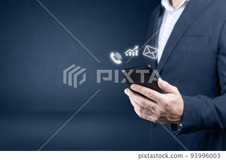 Online business. businessman holding the phone with mail, phone, Analytics, charts, email icon on dark blue background. copy space Online business. businessman holding the phone with mail, phone, Analytics, charts, email icon on dark blue background. copy space 93996003