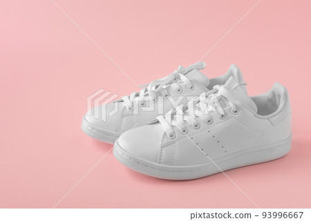 Stylish sneakers. Pair of new white sneakers on pink pastel background. New white leather sneakers sports shoes. Copyspace 93996667