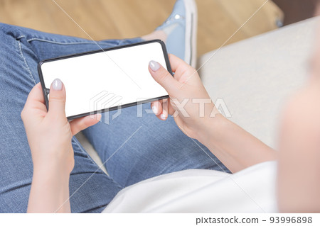 Mockup image of woman's hands holding white mobile phone with blank screen in horizontal position 93996898