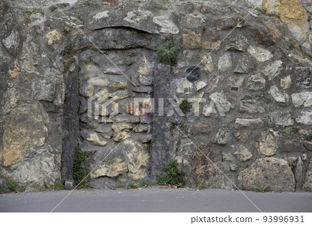 A stone building with a bricked-up door 93996931