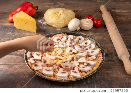 woman making homemade pizza. Preparing pizza, close-up of hand topping pizza with cheese on dark wooden rustic background woman making homemade pizza. Preparing pizza, close-up of hand topping pizza with cheese on dark wooden rustic background 93997290