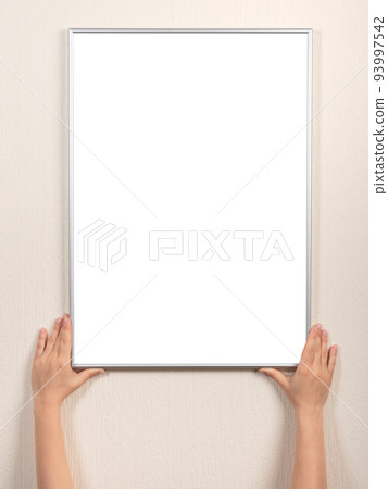 picture frame of hand is hanging on the wall. woman hanging blank posteron wall. diploma mockup picture frame of hand is hanging on the wall. woman hanging blank posteron wall. diploma mockup 93997542