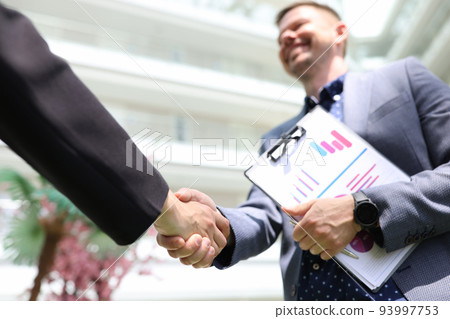 Handshake of businessmen with financial analytics charts Handshake of businessmen with financial analytics charts 93997753