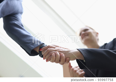 Businessman and woman shaking hands in office closeup Businessman and woman shaking hands in office closeup 93997758