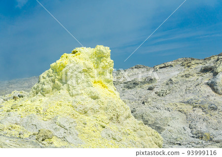 cone of sulfur deposits around a fumarole in a solfataric field against a blue sky cone of sulfur deposits around a fumarole in a solfataric field against a blue sky 93999116