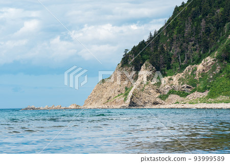 coastal seascape, beautiful lava rocks on the wooded coast of Kunashir island near Cape Stolbchaty coastal seascape, beautiful lava rocks on the wooded coast of Kunashir island near Cape Stolbchaty 93999589