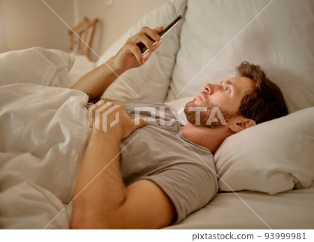 Social media, mobile app and relax man with smartphone using the internet or online website content at night in his bedroom with home wifi. Serious insomnia person reading blog for sleep health tips Social media, mobile app and relax man with smartphone using the internet or online website content at night in his bedroom with home wifi. Serious insomnia person reading blog for sleep health tips 93999981