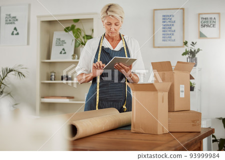 Packing parcel or package in shop, online fashion order on tablet, clothes boutique or design workshop. Mature tailor or seamstress packaging, boxing or wrapping clothing product for courier delivery Packing parcel or package in shop, online fashion order on tablet, clothes boutique or design workshop. Mature tailor or seamstress packaging, boxing or wrapping clothing product for courier delivery 93999984