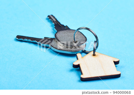 Trinket in the form of a wooden house with the keys to the apartment on the blue background Trinket in the form of a wooden house with the keys to the apartment on the blue background 94000068