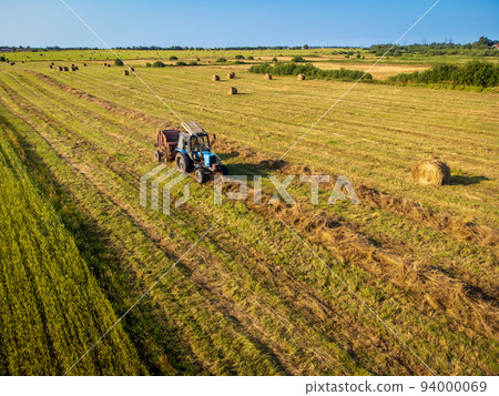 Tractor bailing dry grass in countryside Tractor bailing dry grass in countryside 94000069