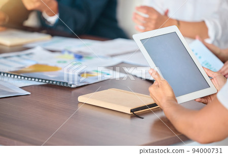 Tablet, business meeting and mock up screen at corporate office desk with investors or team. Management, notes and analytics data report on digital technology for conference or presentation. 94000731