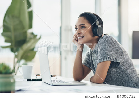 Happy, smiling business woman day dreaming of success at her office desk in a modern office. Female office worker enjoying a podcast or songs during a break in a corporate company over copy space. Happy, smiling business woman day dreaming of success at her office desk in a modern office. Female office worker enjoying a podcast or songs during a break in a corporate company over copy space. 94000732