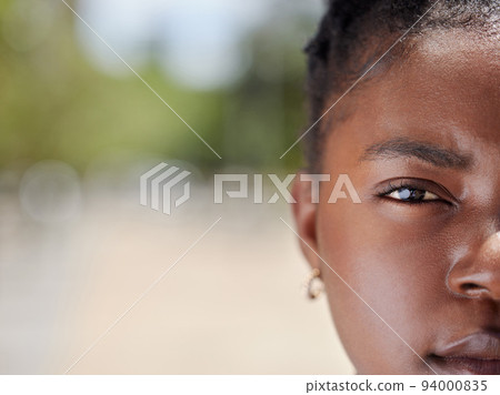 Serious face portrait of a woman with clear skin outdoors in natural light and background. African, female eye and head zoom focus isolated in nature with a confident and vision empowerment look 94000835