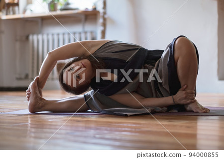 Woman practicing yoga lesson, breathing, doing twisted exercise, working out 94000855
