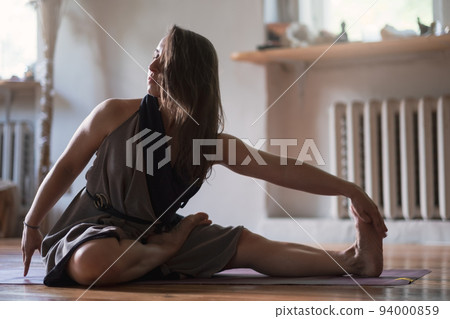 Woman practicing yoga lesson, breathing, doing twisted exercise, working out 94000859
