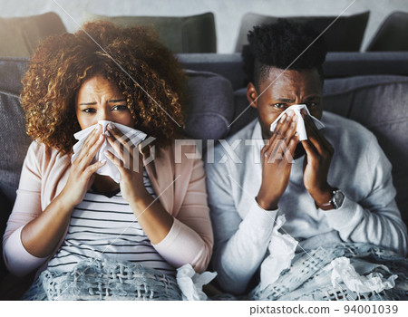Portrait of a sick couple suffering from the flu, corona or sinus at home together, feeling unwell and weak. Girlfriend and boyfriend in quarantine, recovering from a virus and resting indoors Portrait of a sick couple suffering from the flu, corona or sinus at home together, feeling unwell and weak. Girlfriend and boyfriend in quarantine, recovering from a virus and resting indoors 94001039