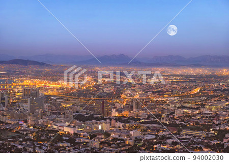 Copy space night view of city buildings with electricity lights, infrastructure and moon with mountain background in travel destination. Cape Town, South Africa downtown centre and urban architecture Copy space night view of city buildings with electricity lights, infrastructure and moon with mountain background in travel destination. Cape Town, South Africa downtown centre and urban architecture 94002030