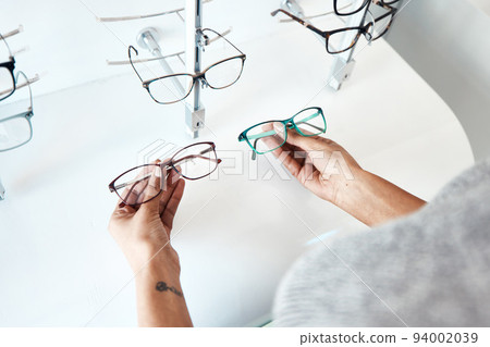 Buying, looking and shopping for glasses at a retail eyewear store and optometrist inside. Customer holding shop stock trying to decide on a new modern style, trendy and stylish frames to buy on sale Buying, looking and shopping for glasses at a retail eyewear store and optometrist inside. Customer holding shop stock trying to decide on a new modern style, trendy and stylish frames to buy on sale 94002039