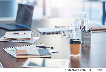 Desk, empty office workspace on a wooden desk or table in a corporate boardroom. Laptop or computer in a digital marketing agency or IT company with notebooks and a coffee cup 94002208