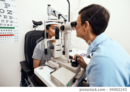 Eye and vision test, exam or screening with an optometrist, optician or ophthalmologist and a patient using an ophthalmoscope. Testing and checking eyesight for prescription glasses or contact lenses Eye and vision test, exam or screening with an optometrist, optician or ophthalmologist and a patient using an ophthalmoscope. Testing and checking eyesight for prescription glasses or contact lenses 94002243