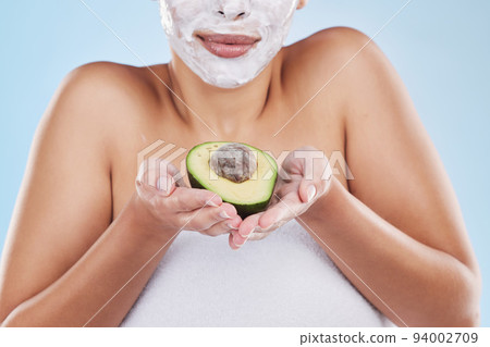 Hands, avocado and skincare face mask of a woman in beauty and cosmetic facial on a blue studio background. Female in health, skin and body care holding green fruit for nutrition, food or diet Hands, avocado and skincare face mask of a woman in beauty and cosmetic facial on a blue studio background. Female in health, skin and body care holding green fruit for nutrition, food or diet 94002709